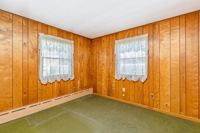 empty room with baseboard heating, wooden walls, and carpet floors