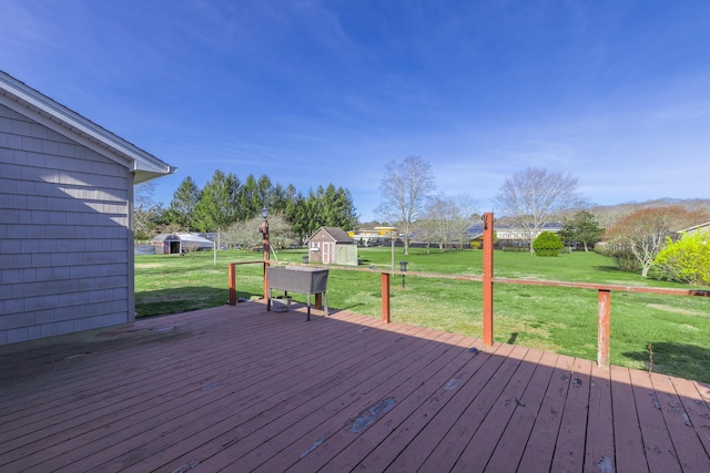 wooden terrace featuring a lawn, a storage unit, and an outdoor structure