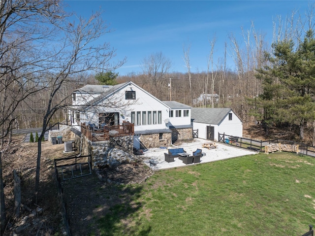 back of property featuring a fenced backyard, a patio, an outdoor living space, a lawn, and stone siding