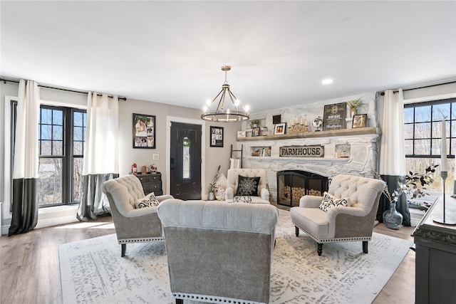living room featuring light wood finished floors, a fireplace, and a notable chandelier