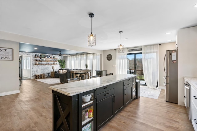 kitchen featuring light wood finished floors, baseboards, appliances with stainless steel finishes, and pendant lighting