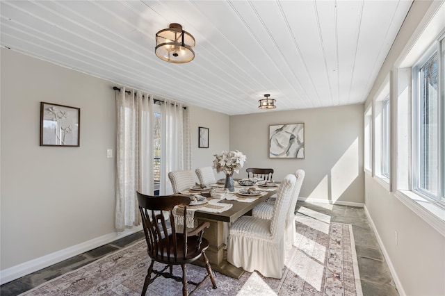 dining area with stone tile floors, a healthy amount of sunlight, and baseboards