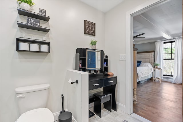bathroom with wood finished floors, connected bathroom, beamed ceiling, baseboards, and toilet