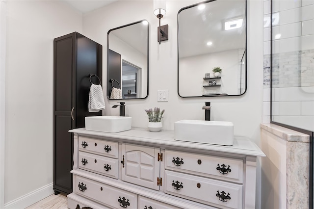 bathroom featuring wood finished floors, baseboards, a sink, and double vanity