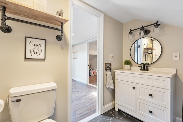 bathroom with tile patterned floors, toilet, baseboards, lofted ceiling, and vanity
