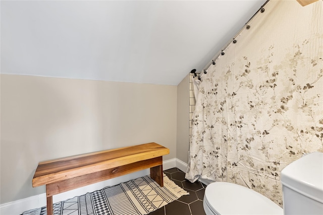 bathroom with lofted ceiling, tile patterned flooring, toilet, a shower with curtain, and baseboards