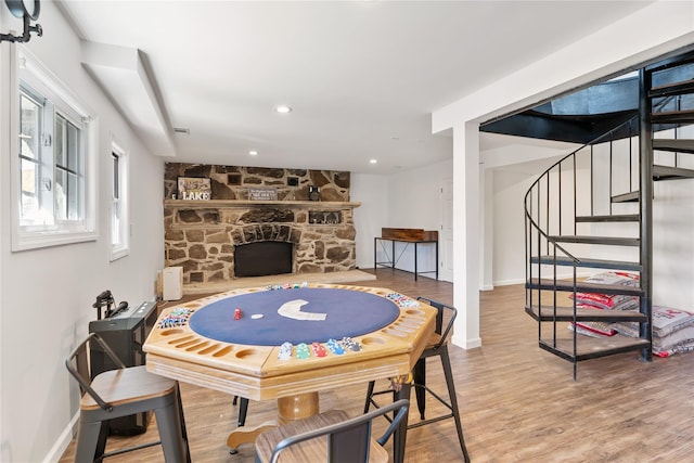 recreation room featuring wood finished floors, baseboards, a fireplace, and recessed lighting