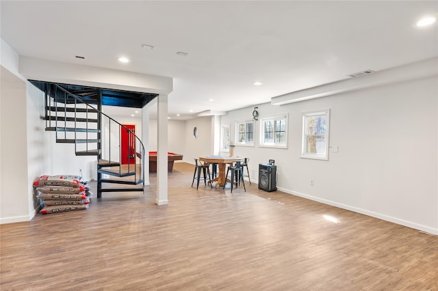 basement with baseboards, wood finished floors, visible vents, and stairs