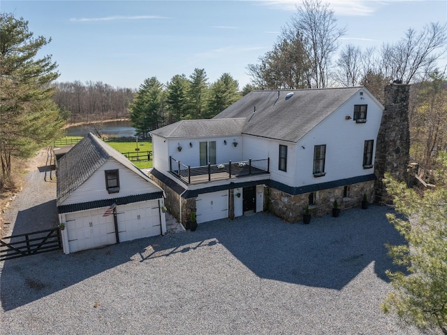 exterior space with gravel driveway, fence, stone siding, and a shingled roof