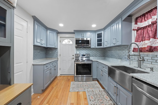 kitchen with gray cabinetry, a sink, and stainless steel appliances