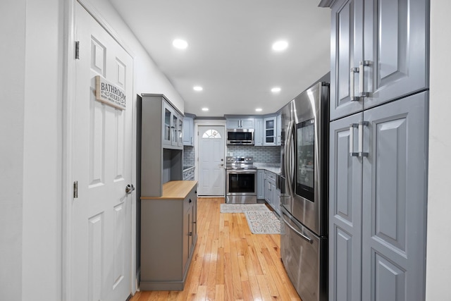 kitchen with tasteful backsplash, light wood-style floors, appliances with stainless steel finishes, and gray cabinetry