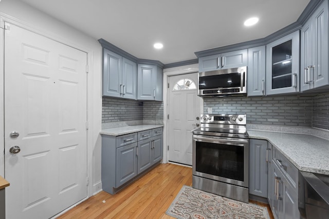 kitchen with stainless steel appliances, glass insert cabinets, backsplash, and gray cabinets