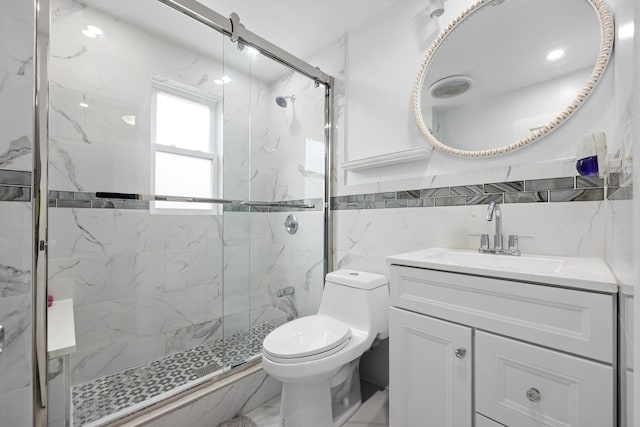 bathroom with a marble finish shower, tile walls, vanity, and toilet