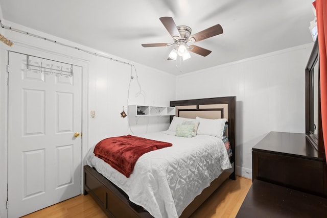bedroom featuring light wood finished floors, crown molding, and ceiling fan