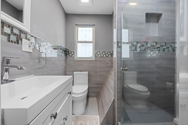 bathroom with toilet, a stall shower, vanity, and tile walls