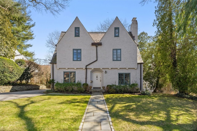 view of front of property featuring stucco siding, a chimney, and a front yard