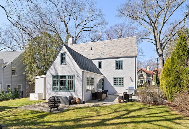 back of house featuring a patio area, a fire pit, stucco siding, a chimney, and a lawn