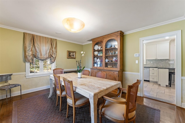 dining space featuring crown molding, baseboards, and wood finished floors