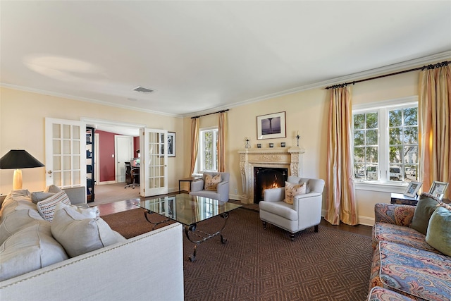 living room with french doors, baseboards, ornamental molding, visible vents, and a fireplace with flush hearth