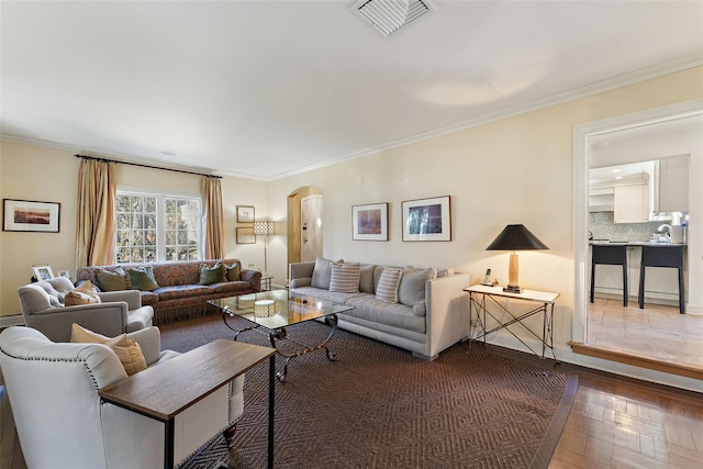 living area featuring crown molding, visible vents, wood finished floors, and arched walkways