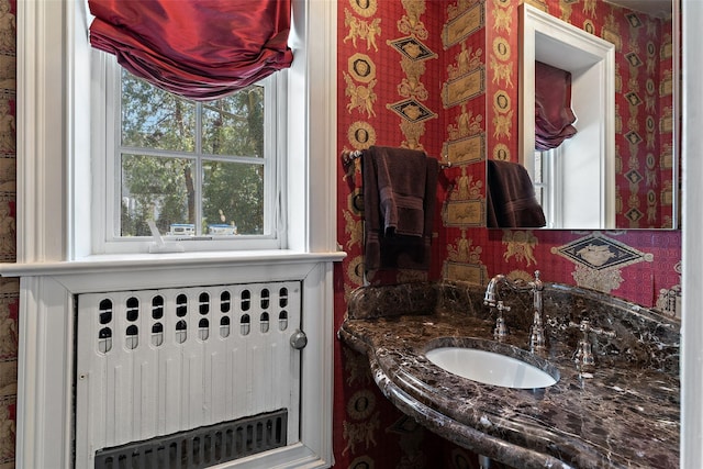 bathroom featuring a sink, wallpapered walls, and radiator heating unit