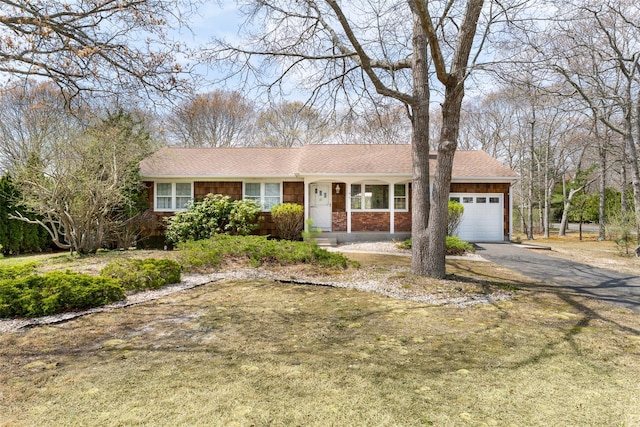 ranch-style home with covered porch, aphalt driveway, a shingled roof, and an attached garage