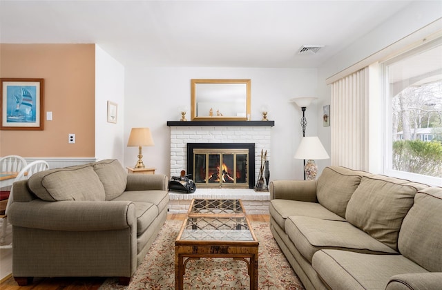 living area featuring visible vents, wood finished floors, and a fireplace