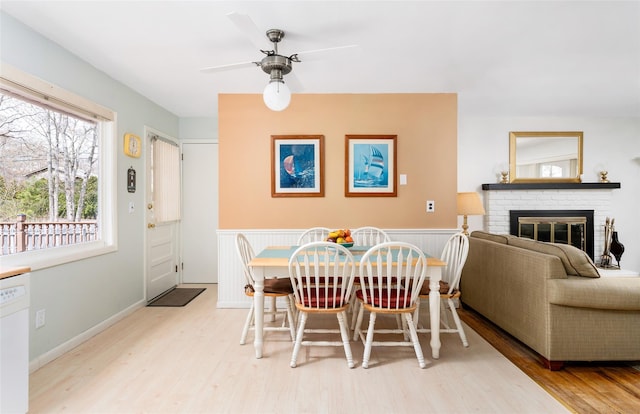 dining area with a fireplace, wood finished floors, and a ceiling fan