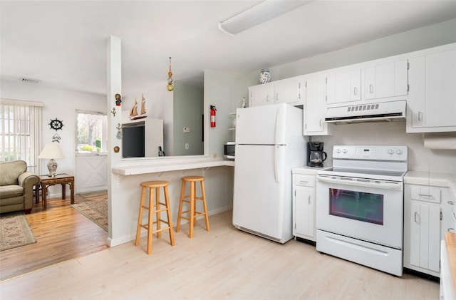 kitchen featuring white cabinets, light wood-style flooring, light countertops, under cabinet range hood, and white appliances