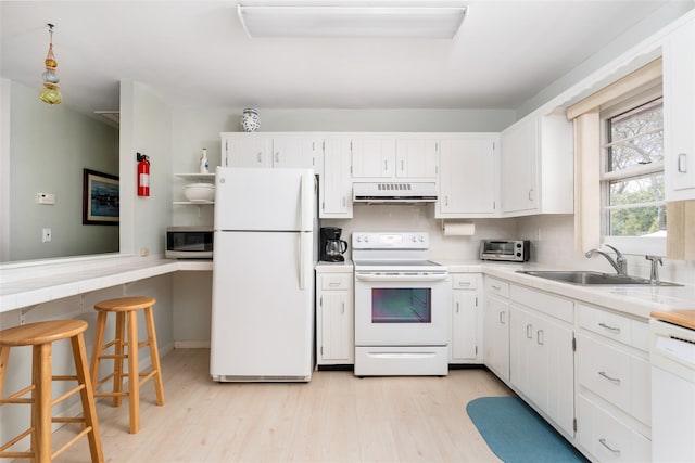 kitchen with a sink, light wood-style floors, under cabinet range hood, a toaster, and white appliances