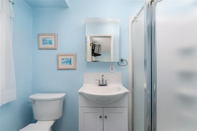 full bathroom featuring toilet, vanity, decorative backsplash, and a stall shower