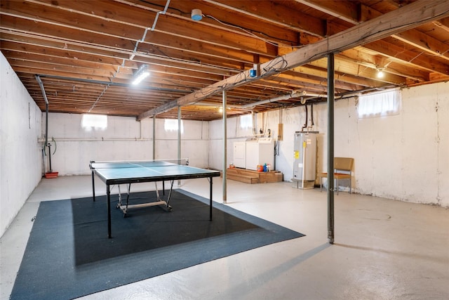 playroom featuring washer and dryer, water heater, and finished concrete floors