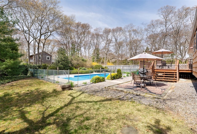view of swimming pool featuring a deck, fence, a fenced in pool, a patio area, and a lawn