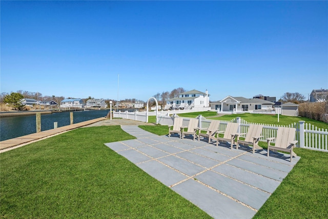 view of home's community featuring a residential view, a yard, fence, and a water view