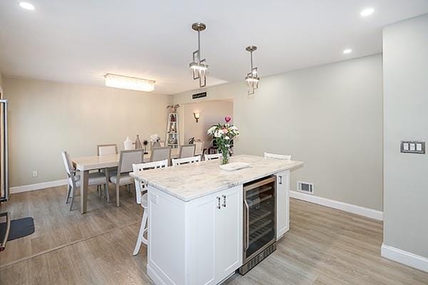 80 Lauren Ave, Dix Hills, NY 11746 - kitchen with beverage cooler, light wood-style floors, baseboards, a center island, and recessed lighting