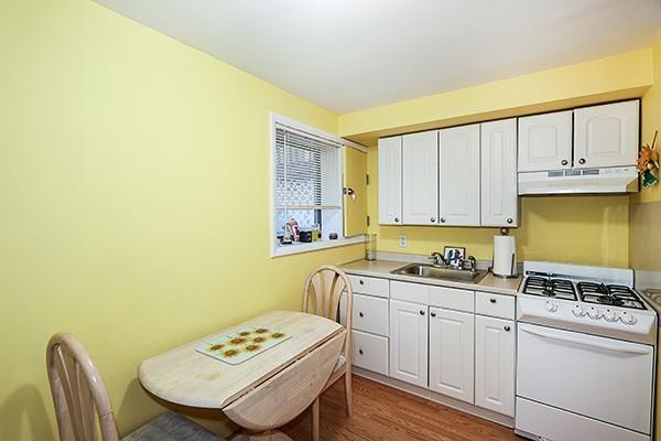 80 Lauren Ave, Dix Hills, NY 11746 - kitchen featuring white range with gas stovetop, under cabinet range hood, a sink, and white cabinetry