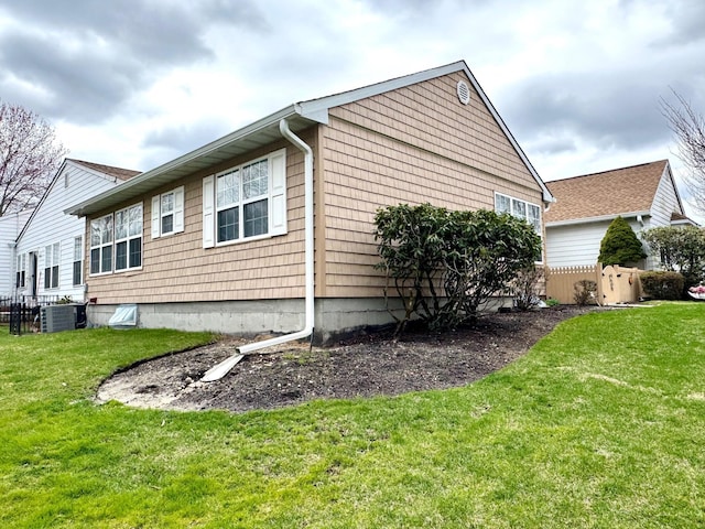 view of side of home featuring central air condition unit, fence, and a lawn