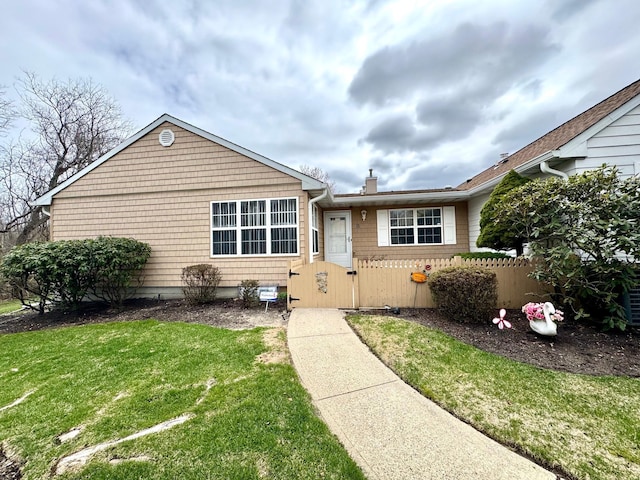view of front of house with a chimney, a front yard, and fence