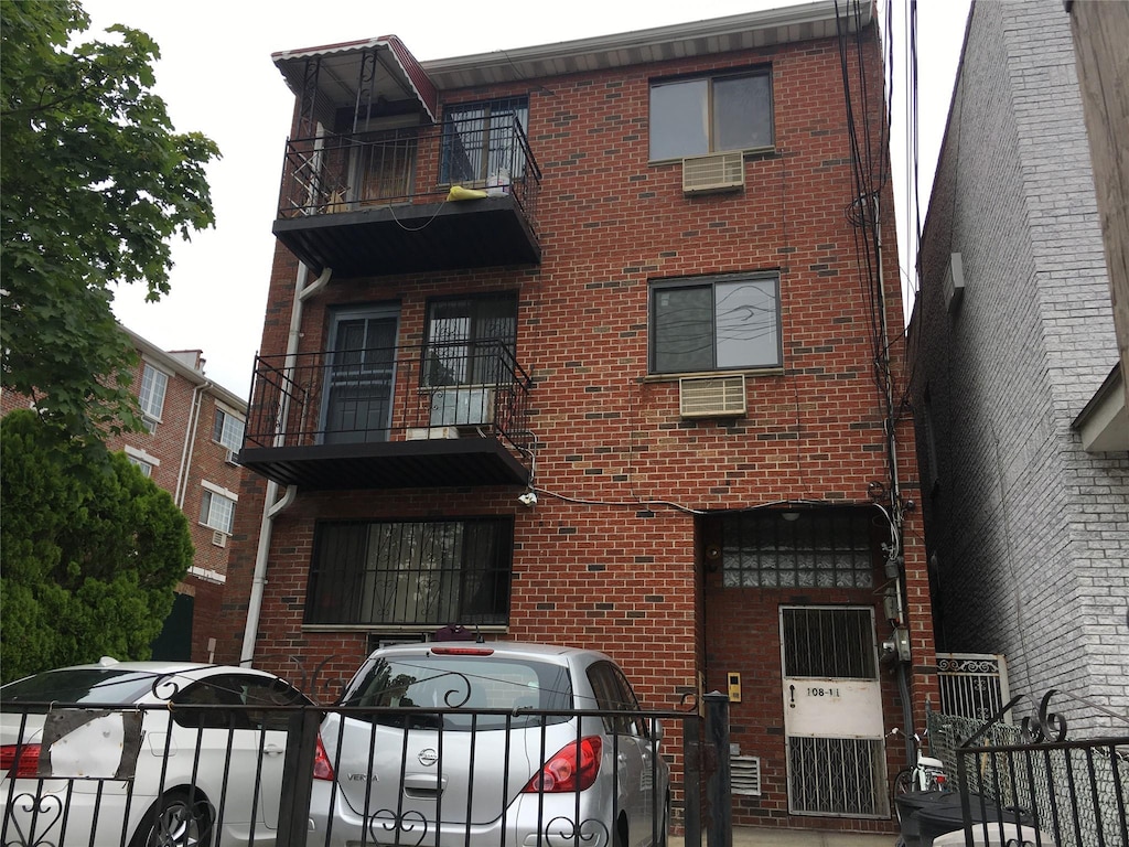 view of front of house with brick siding and a balcony