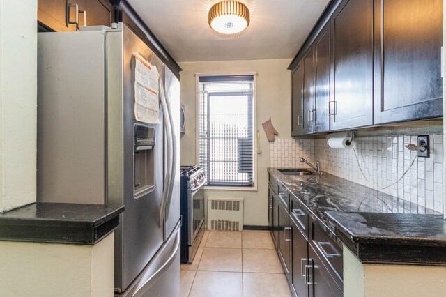 kitchen featuring decorative backsplash, a sink, appliances with stainless steel finishes, dark brown cabinets, and radiator