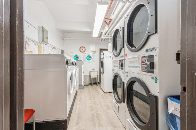 shared laundry area featuring stacked washer / drying machine, light wood finished floors, and washing machine and dryer
