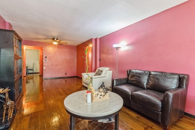 living area featuring hardwood / wood-style floors, ceiling fan, and baseboards