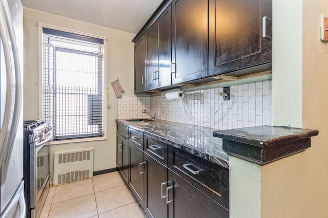 kitchen featuring tasteful backsplash, dark brown cabinets, a sink, stainless steel appliances, and radiator