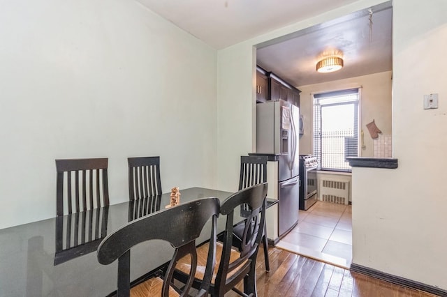 dining space with wood finished floors and radiator