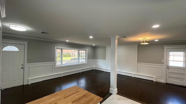 foyer with ornamental molding, decorative columns, wood finished floors, and wainscoting
