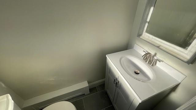 half bath with vanity, baseboards, tile patterned flooring, and toilet
