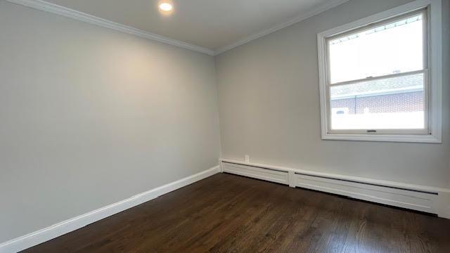 spare room featuring ornamental molding, baseboards, dark wood-style floors, baseboard heating, and recessed lighting