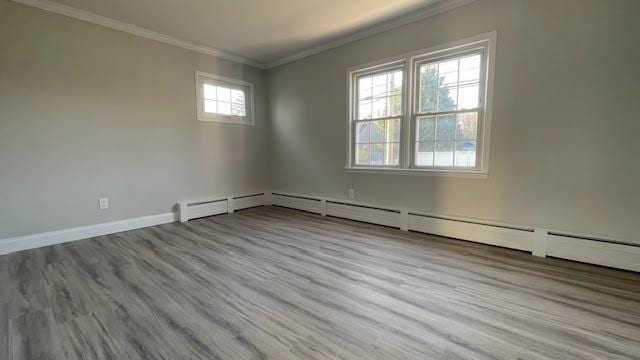 spare room featuring crown molding, baseboards, and wood finished floors