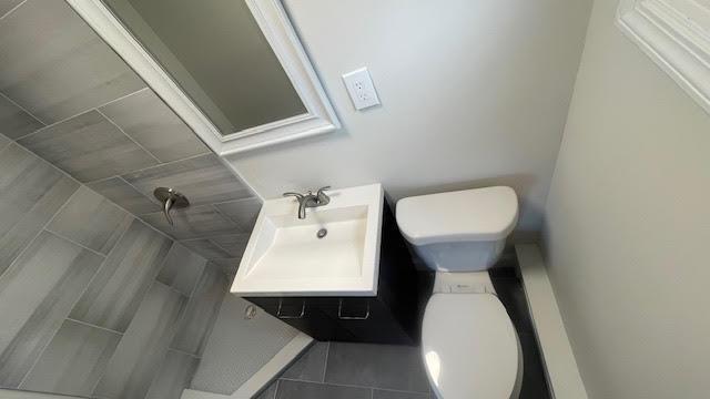 full bathroom with toilet, tile patterned floors, a tile shower, and vanity