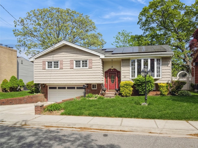 915 Derrick Adkins Ln, West Hempstead, NY 11552 - raised ranch featuring concrete driveway, roof mounted solar panels, a front lawn, and an attached garage